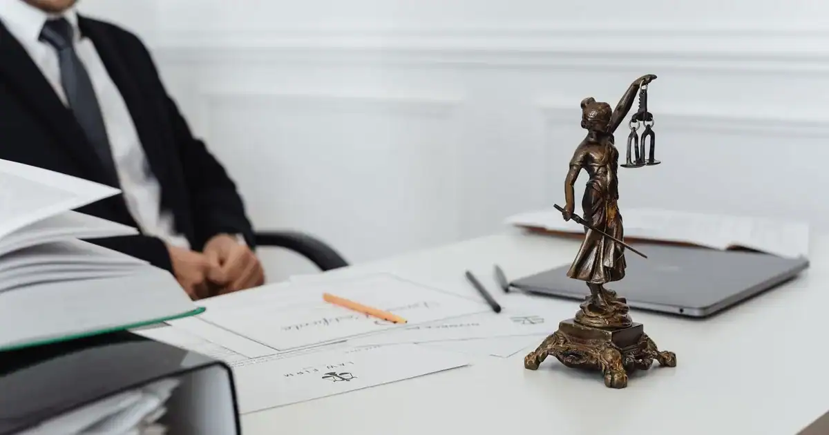 A legal professional's workspace featuring Lady Justice statue, documents, and a laptop. - FAS Local