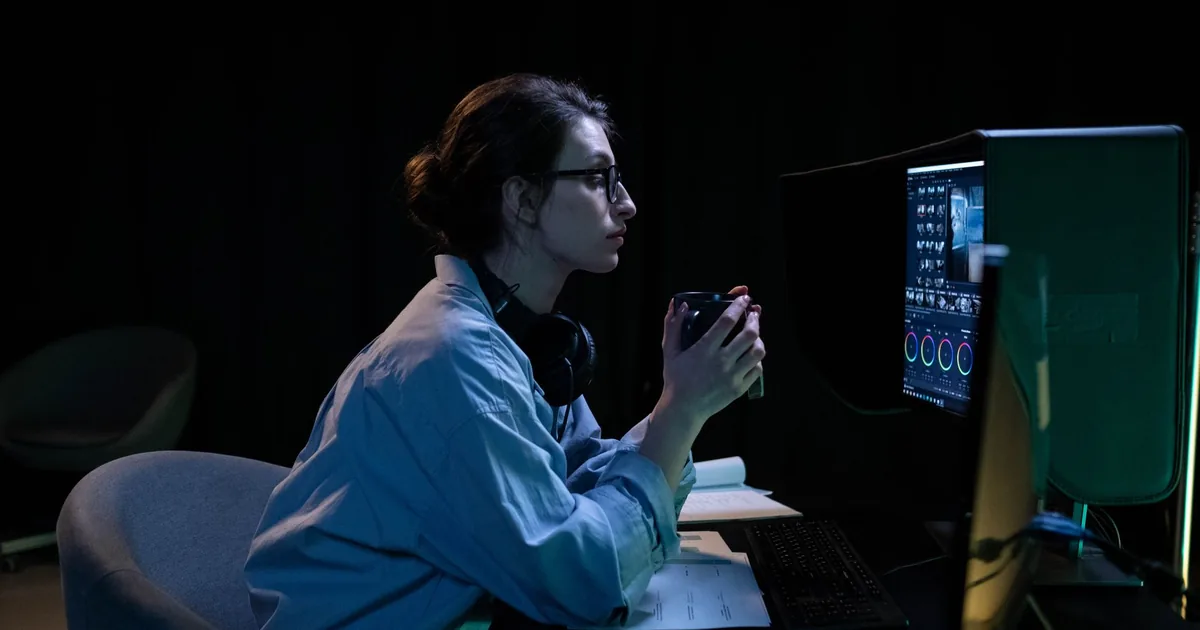 Focused woman reviews MTPE prices on a computer, mug in hand.