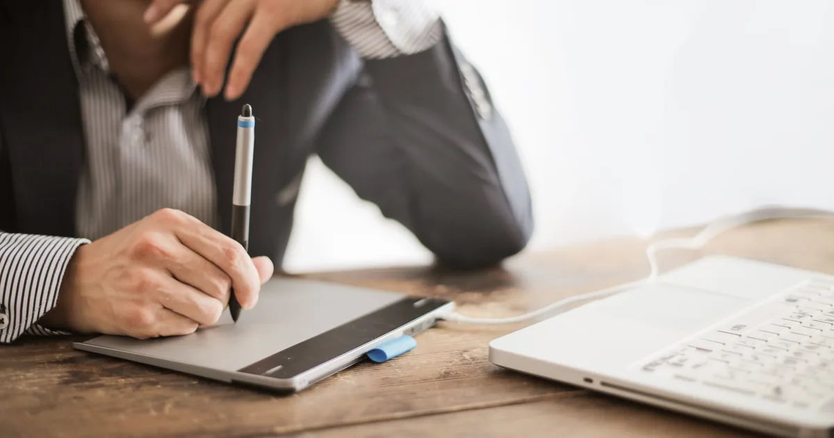 Elegant man using laptop & graphic tablet for MTPE quality evaluation.
