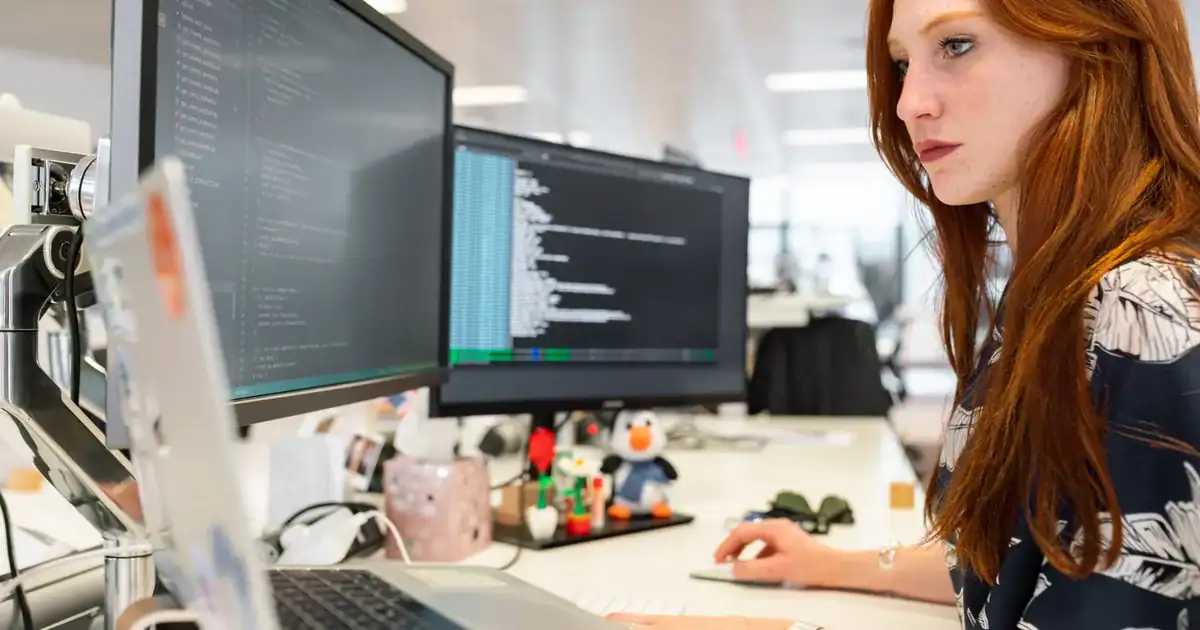 Software engineer coding on dual monitors, calculating MTPE rates.