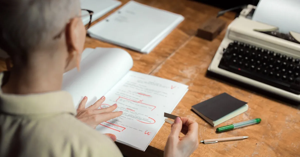 Woman proofreading a script with red pen marks, a step in translation and proofreading.