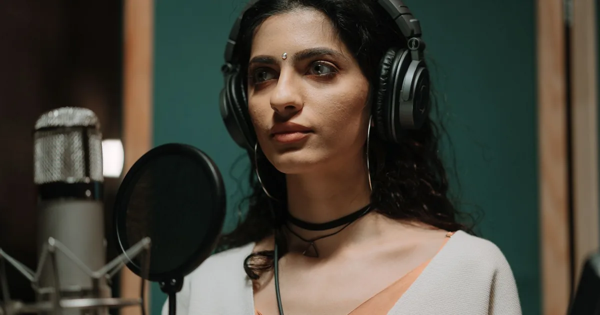 Female singer in headphones records vocals, impacting voice over pricing.