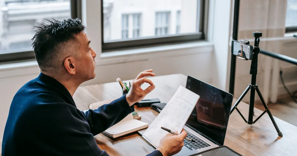 Man using laptop and smartphone for a video call in an office setting. - FAS Localize