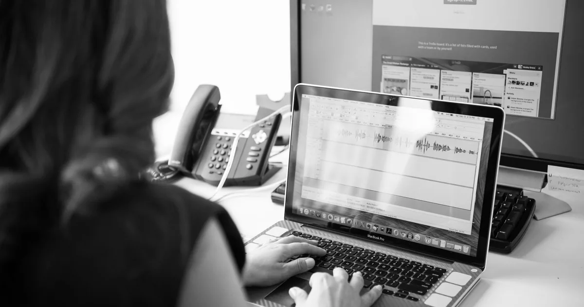 Woman working on laptop, dual monitors, comparing DeepL vs Google Translate MTPE.