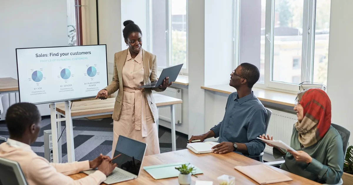 Diverse team engaged in a business presentation with charts on the screen in a modern office setting