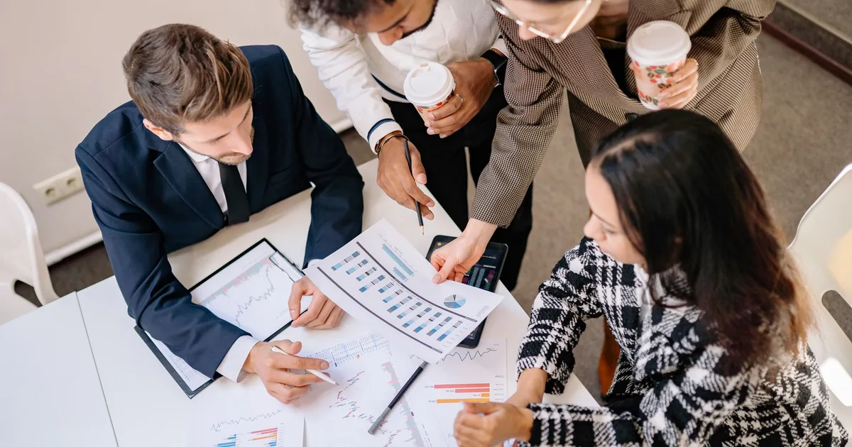 Diverse team analyzing graphs & charts to understand localization cost.
