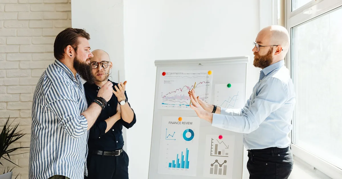 Professionals discuss financial charts, symbolizing MTPE cost savings.