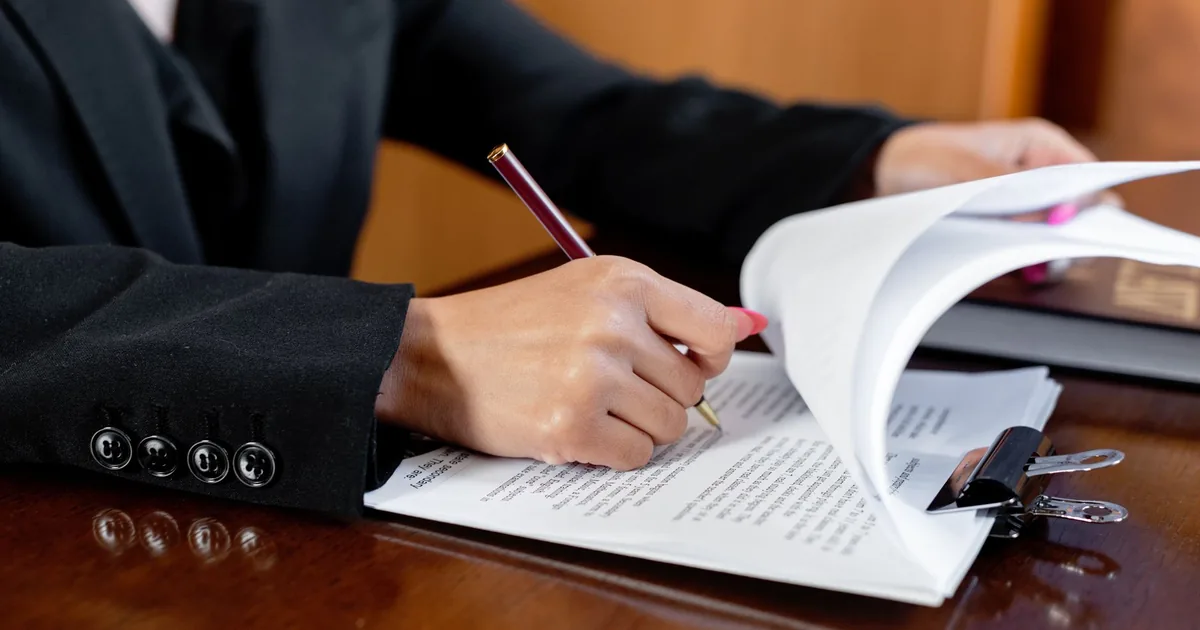 Woman's hand signing legal document, related to sworn translation.