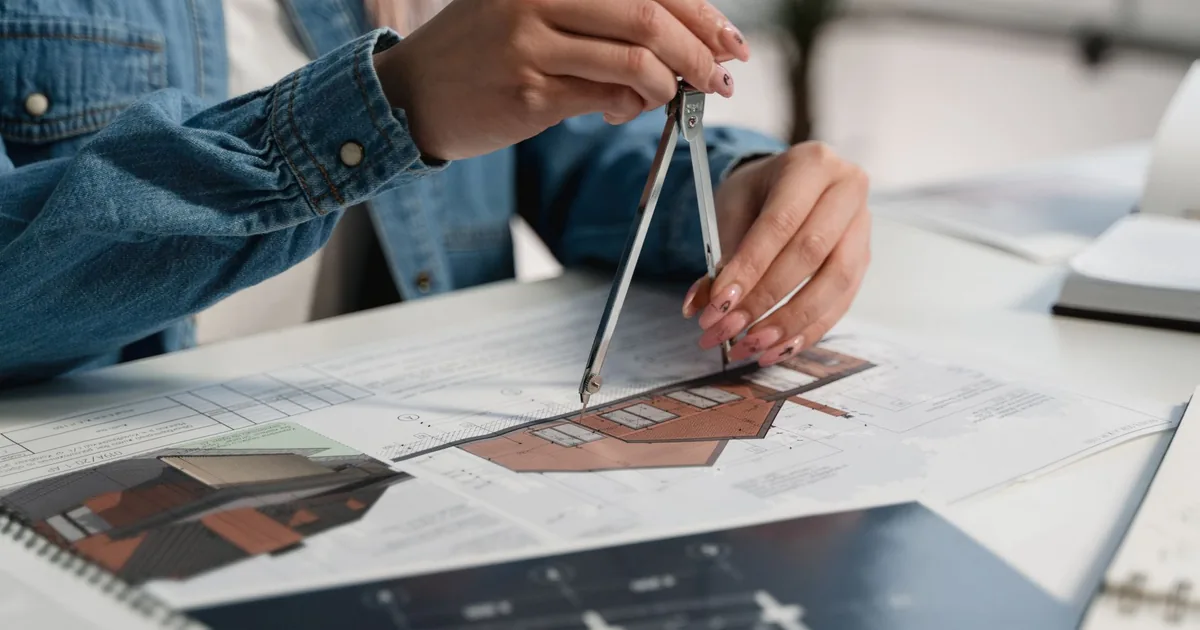 Professional using compass on blueprints for technical translation services.