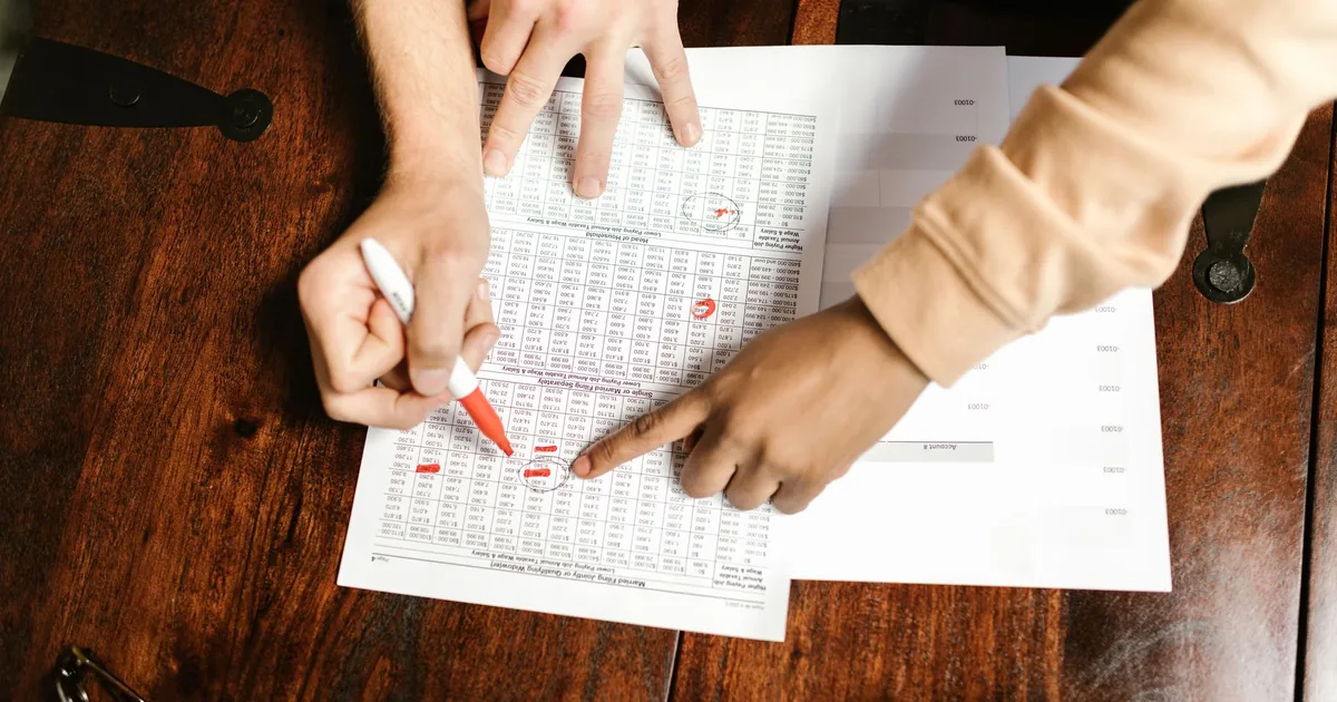 Two hands mark financial documents, ensuring translation quality assurance.