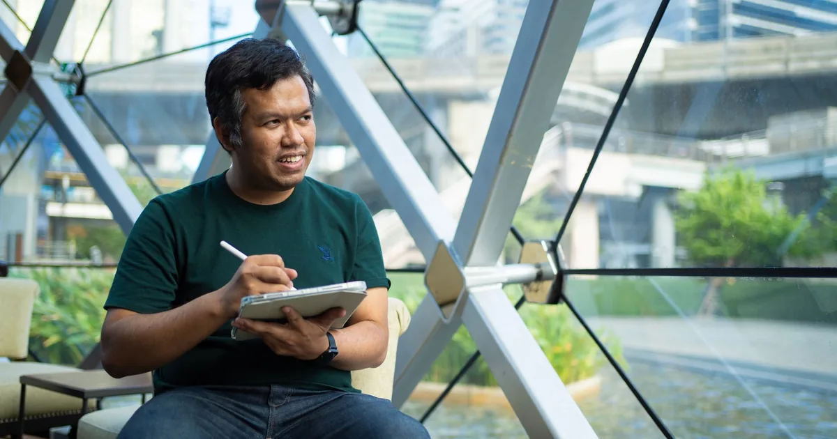 Bangkok café: Man sketches on tablet, ensuring translation quality assurance.